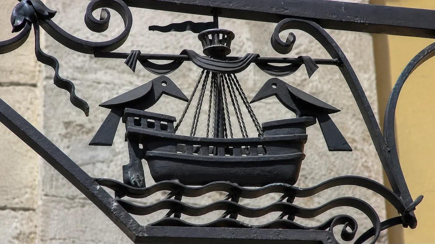 A wrought-iron sign with a ship and two ravens, echoing the symbols of Lisbon